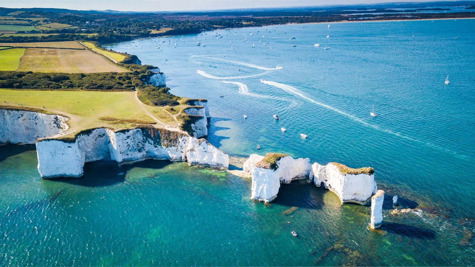 Aerial view of Old Harry Rocks with blue waters and boats.