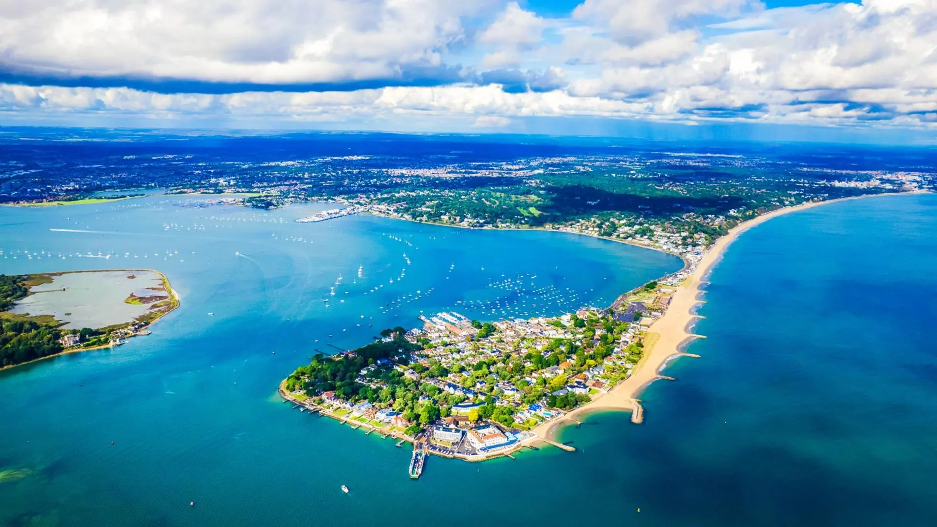 Aerial view of Sandbanks with beautiful blue waters, boats, and stunning harbour scenery.