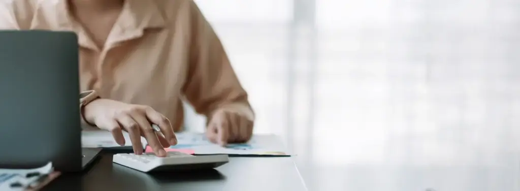 Woman using a calculator while considering downsizing and maximising equity.